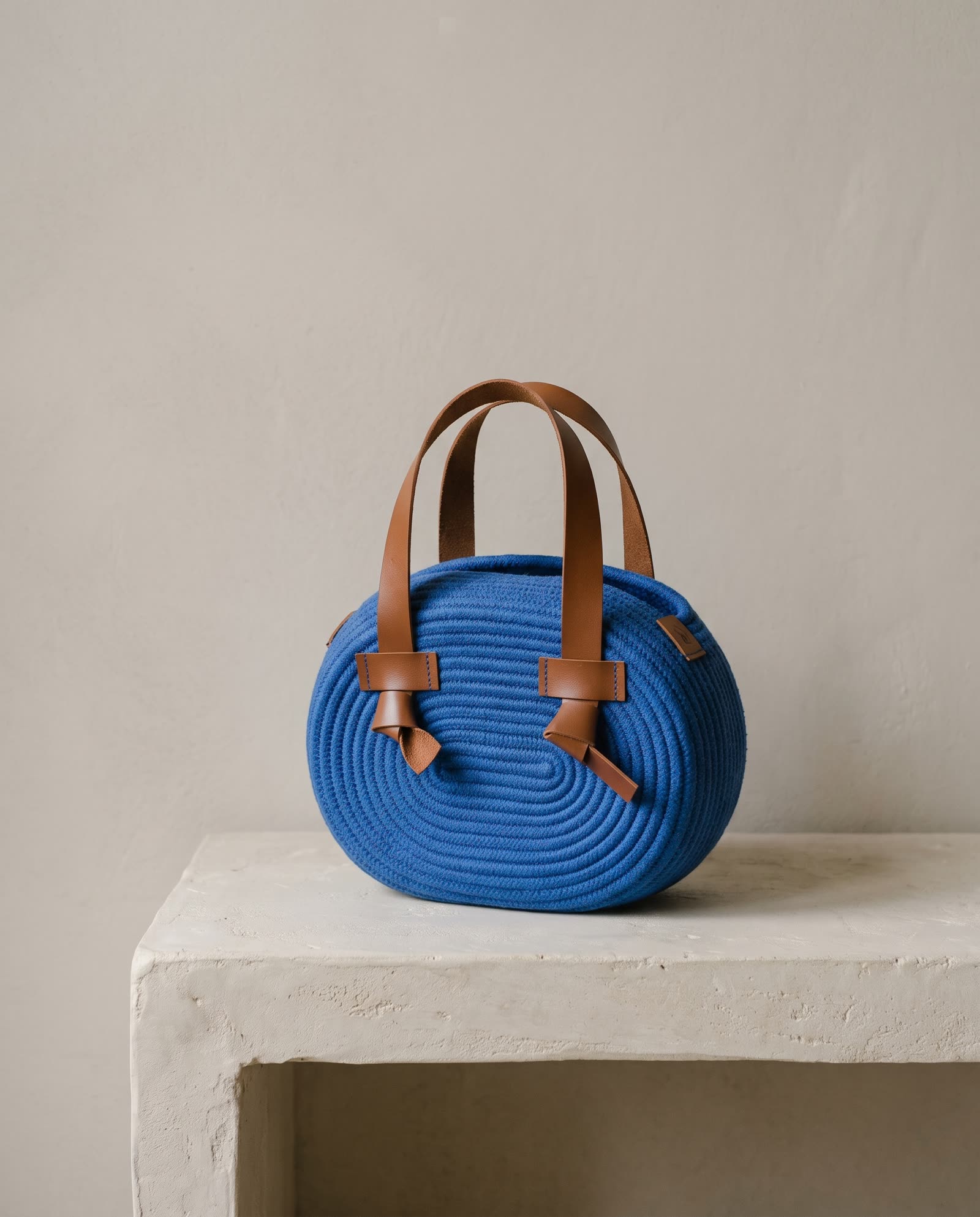 Bolsa redonda de corda azul-cobalto com alças de couro caramelo